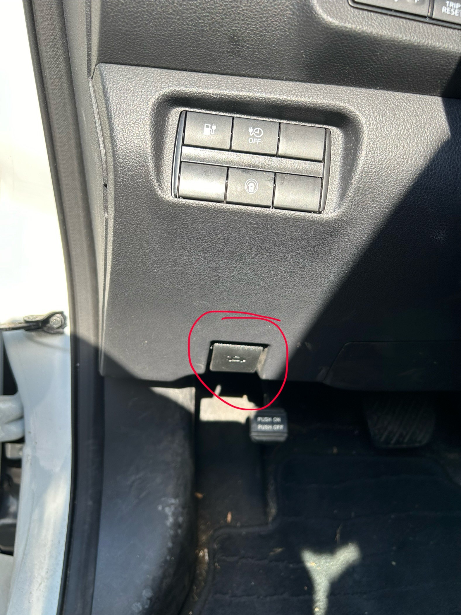 A picture showing the tab you pull to open the hood of a Nissan Leaf.
