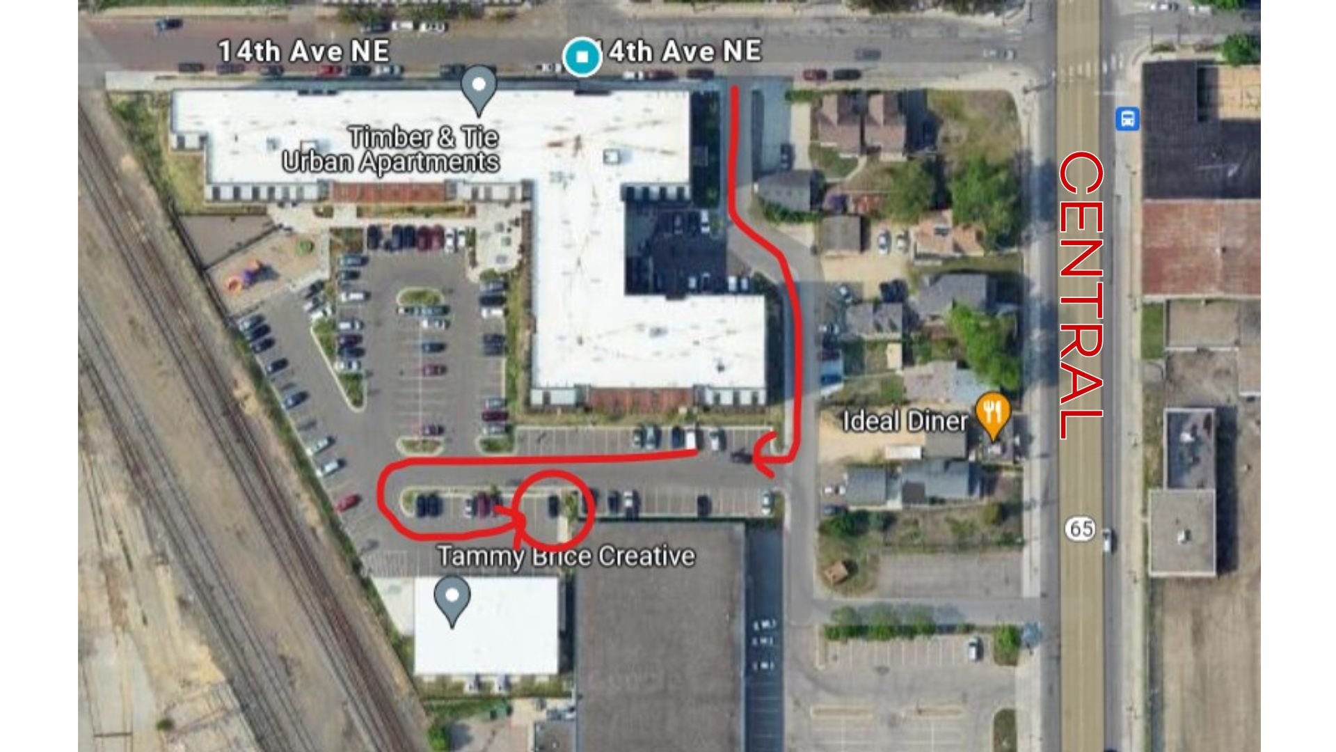 An overhead view of Timber & Tie: Central Ave is on the right side of the image, with an arrow directing from 14th Ave NE south through the parking lot until reaching the hub in the back. 